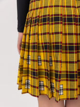 Doppelseitig karierter Faltenminirock mit elastischem Bund und Knopfleiste auf der Vorderseite. Der Rock kann von beiden Seiten getragen werden. Hergestellt aus Naturfasern.