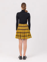 Doppelseitig karierter Faltenminirock mit elastischem Bund und Knopfleiste auf der Vorderseite. Der Rock kann von beiden Seiten getragen werden. Hergestellt aus Naturfasern.