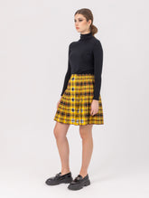 Doppelseitig karierter Faltenminirock mit elastischem Bund und Knopfleiste auf der Vorderseite. Der Rock kann von beiden Seiten getragen werden. Hergestellt aus Naturfasern.