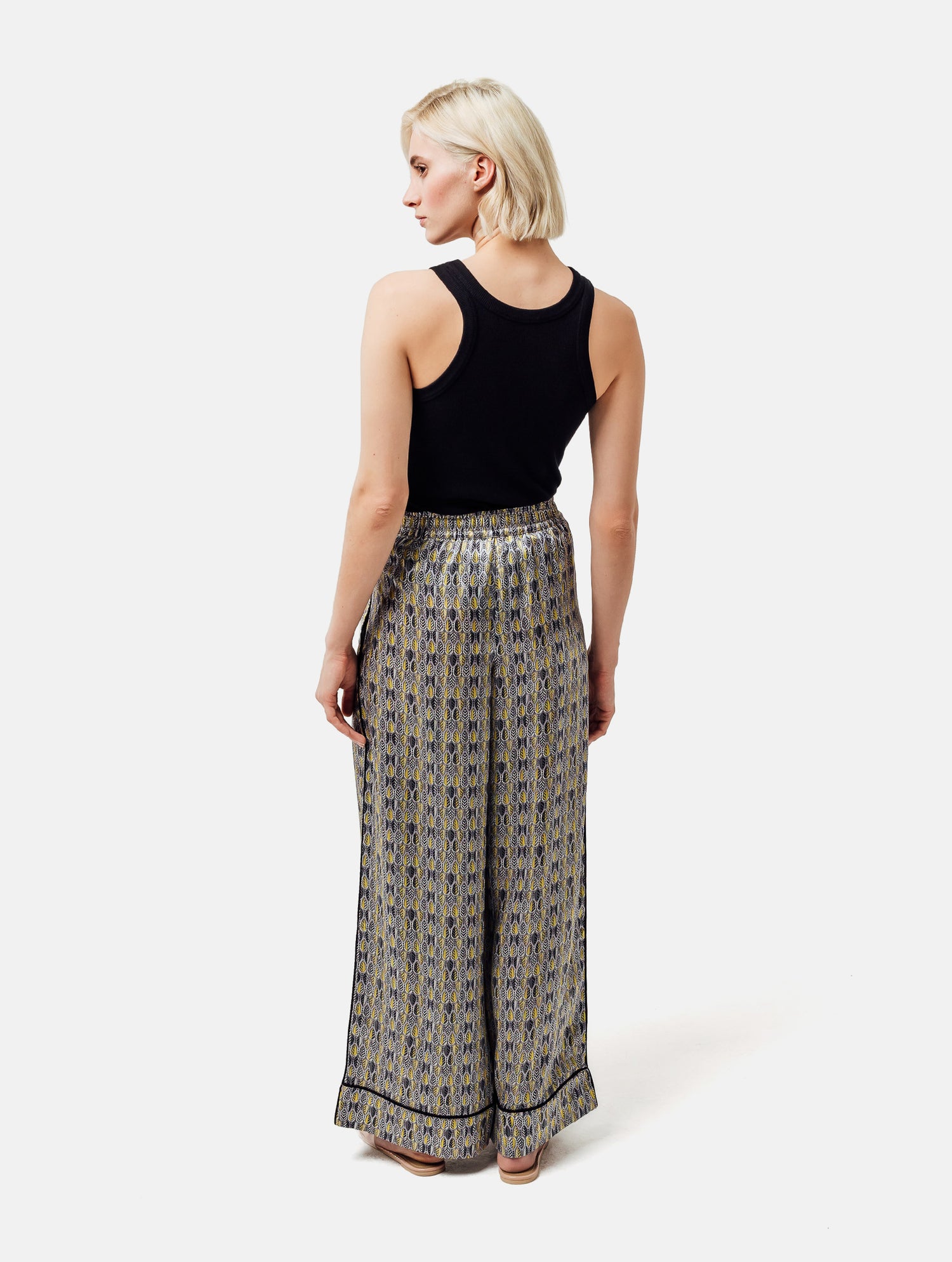 Bedruckte Satin-Seidenhose mit weitem Bein im Pyjama-Stil, elastischem Bund, Seitentaschen und schwarzen Paspeln. Hergestellt aus Naturfaser.
