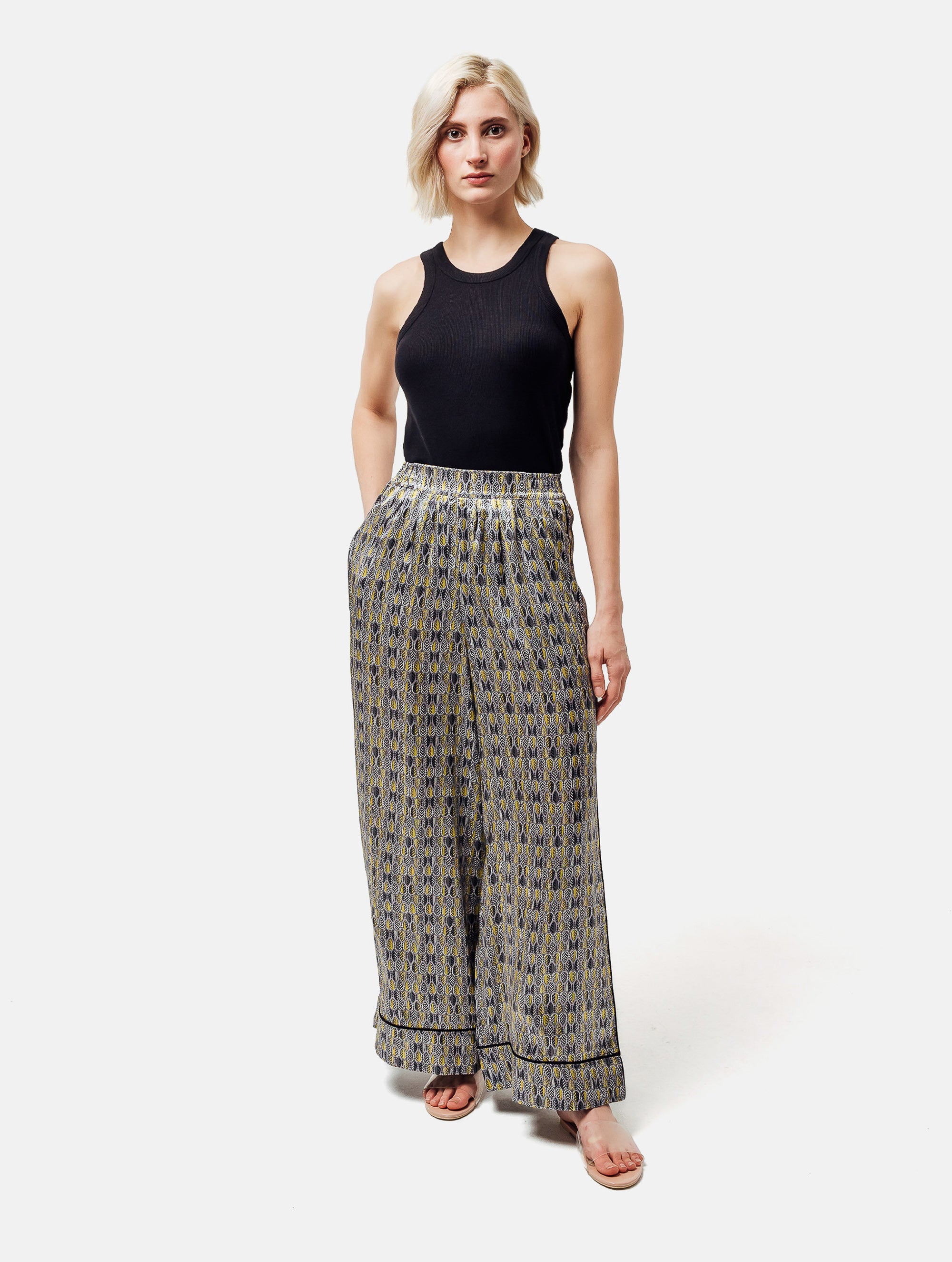 Bedruckte Satin-Seidenhose mit weitem Bein im Pyjama-Stil, elastischem Bund, Seitentaschen und schwarzen Paspeln. Hergestellt aus Naturfaser.