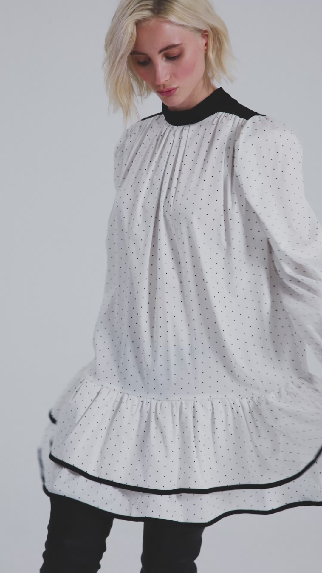 Grade geschnittenes Minikleid aus gepunkteter Baumwolle mit farblich abgesetzten Kragen und Manschetten aus schwarzer Chiffonseide, sowie doppelten Volantssaum. 