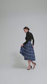 Weit ausgestellter Midirock aus karierter Baumwolle mit in Falten gelegtem und tailliertem Rockbund, versteckten Taschen in der Seitennaht, sowie einem Reißverschluß auf der Rückseite. Dieses Modell ist Teil unserer REBORN-Linie und steht für unsere "Zero-Waste-Politik", da mit Stoff aus einem Deadstock stammt.