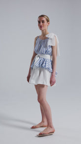 Weit geschnittenes Tanktop aus gestreifter Baumwolle mit weißem Schleifendetail und seperaten Gürtel aus weißer Baumwolle. Versteckte Seitentaschen in den Seitennähten. Dieses Produkt ist Teil unserer Reborn Linie.