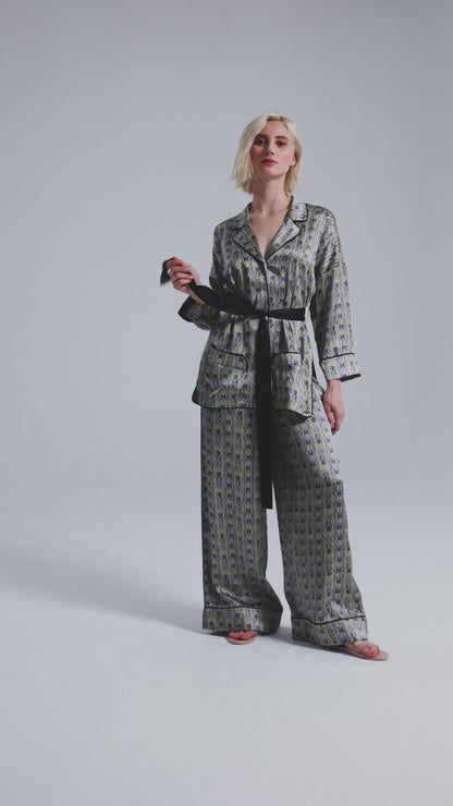 Bedruckte Oversize Seidensatin-Blusenjacke im Pyjama-Stil mit schmalem Revers und Seitenschlitzen sowie schwarzen Paspeln und Seidensatin-Gürtel. Hergestellt aus Naturfaser.