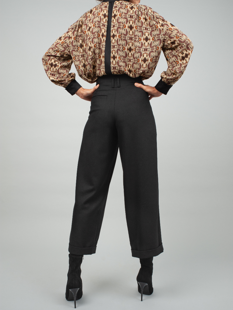 Schwarze Woll-Culotte mit hohem Bund Bundfalten, seitlichen Taschen und kleinen Aufschlägen am Hosenbein